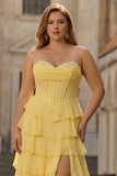 Żółta sukienka balowa bez ramiączek w baskyckiej talii, z falbanami i długą, plus size sukienią na bal z rozcięciem